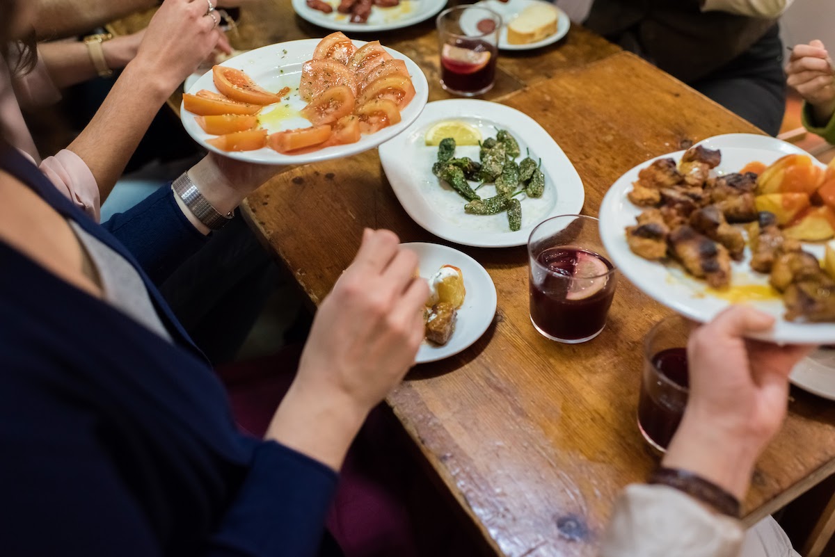 Personas pasando platos compartidos alrededor de una mesa.