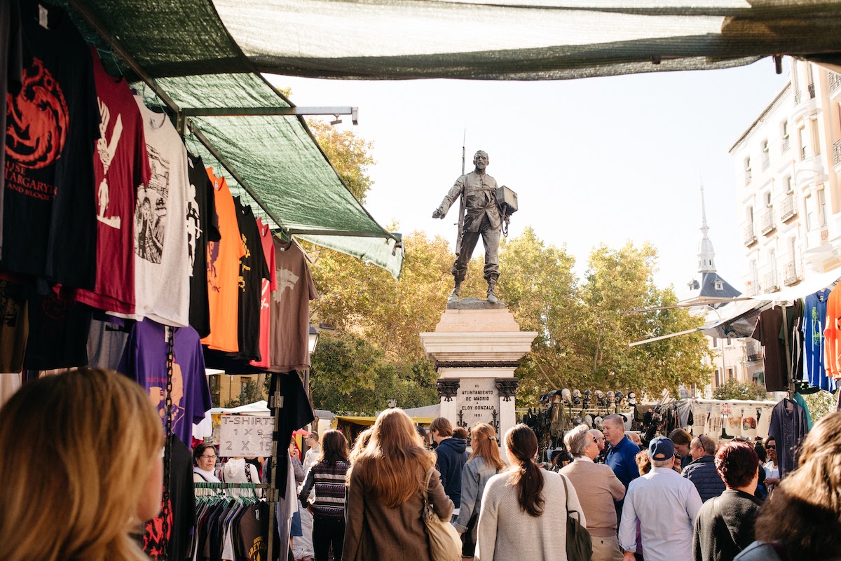 Los puestos del mercado de pulgas se instalan en una concurrida plaza que rodea una gran estatua de metal de un soldado.