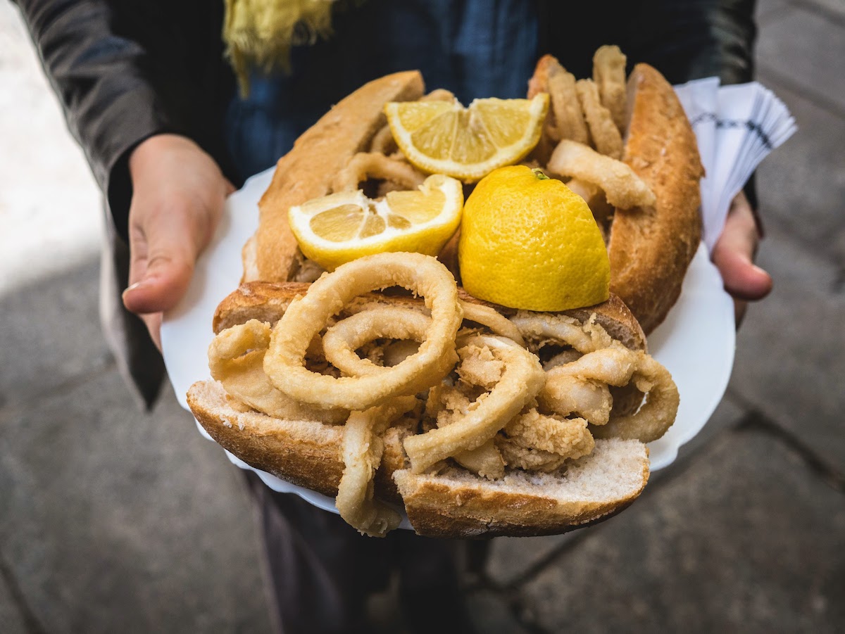 Bandeja de bocadillos de calamares fritos en panecillos con rodajas de limón.
