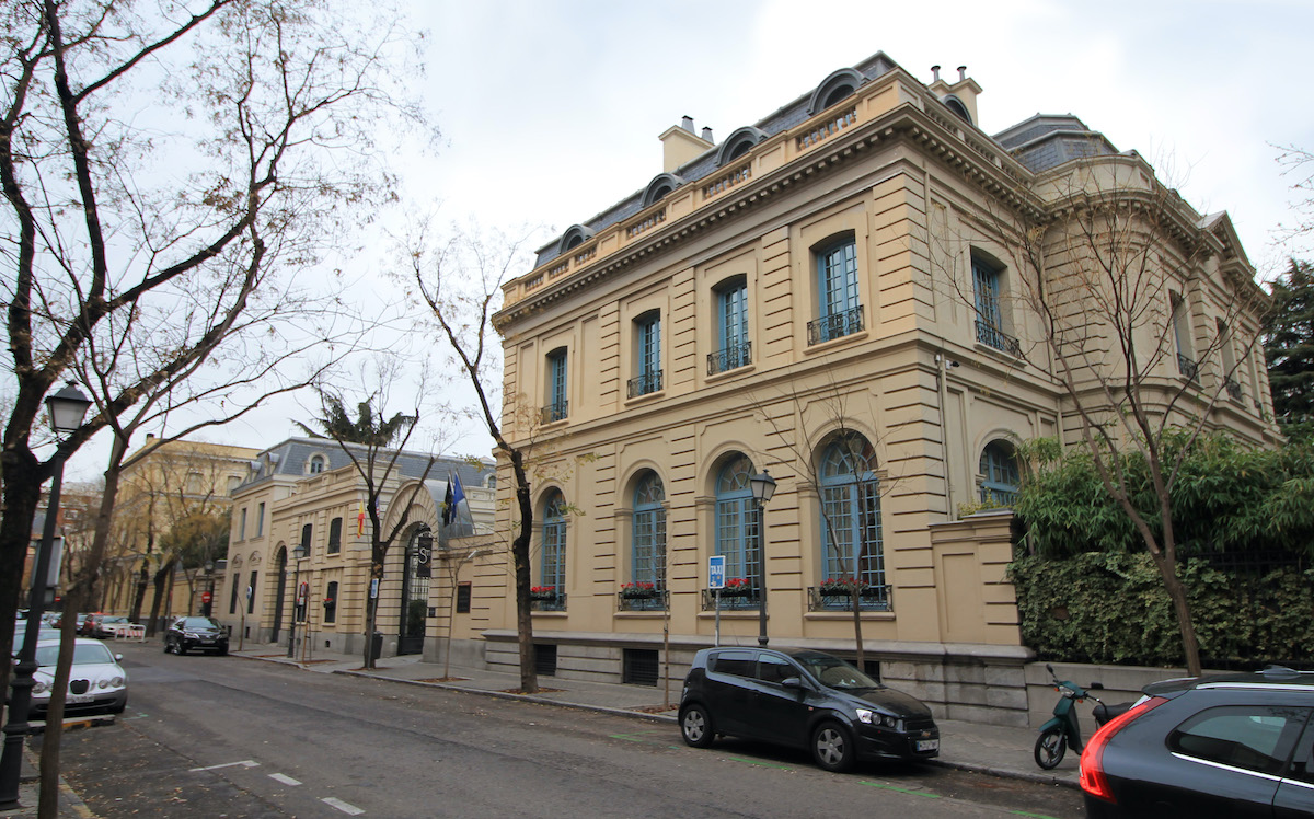 Fachada de un edificio de piedra beige de dos pisos en una calle de la ciudad.