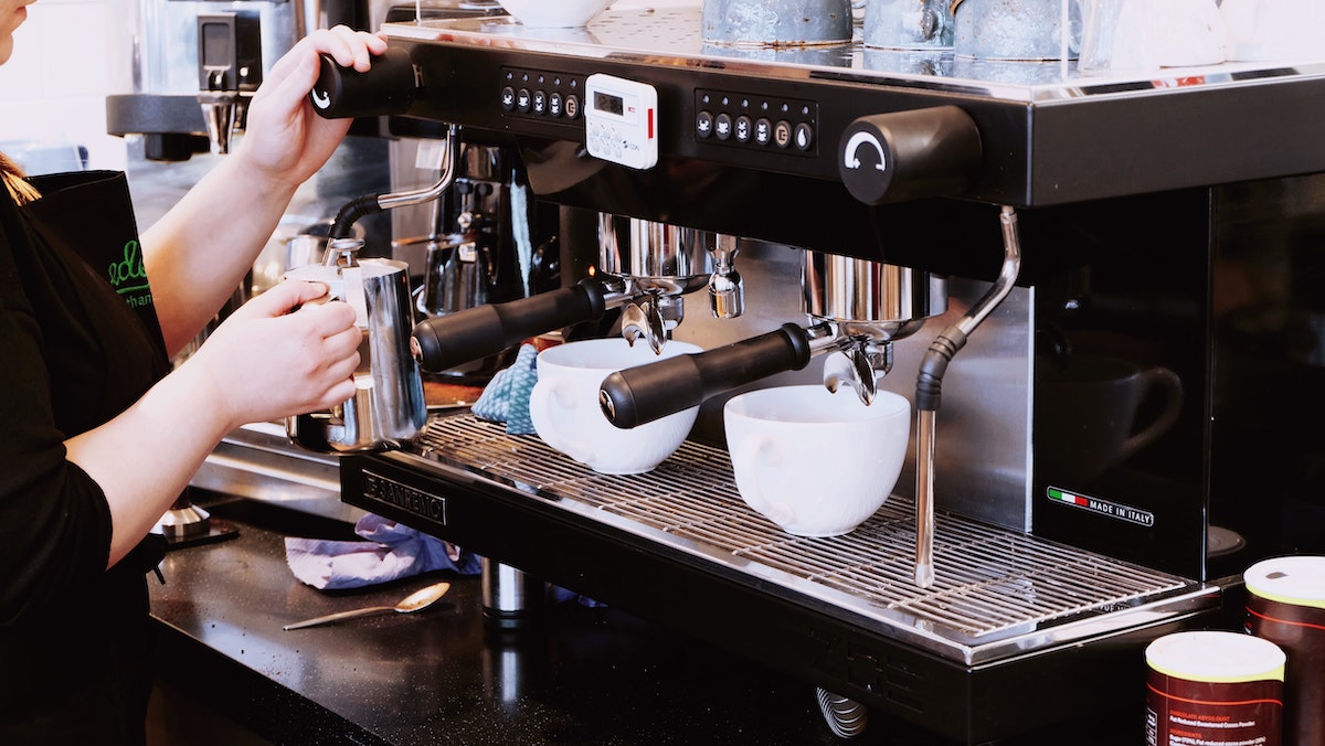 Barista preparando dos tazas de café en una máquina de espresso.