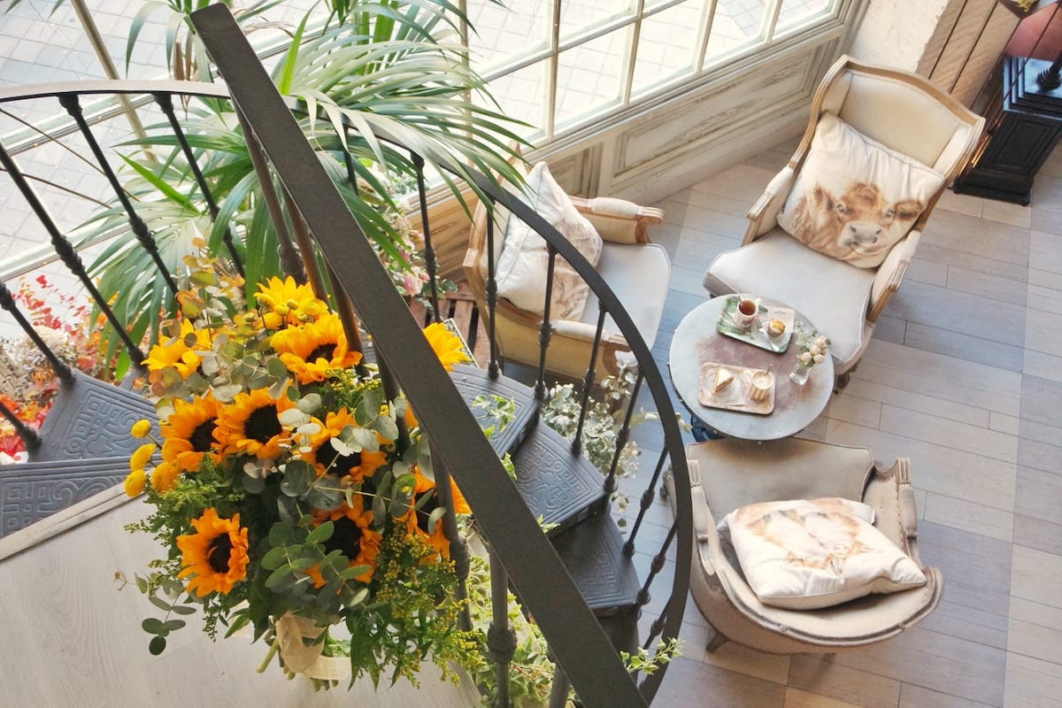 Vista desde arriba de una escalera de caracol decorada con girasoles que baja a un elegante salón de té.