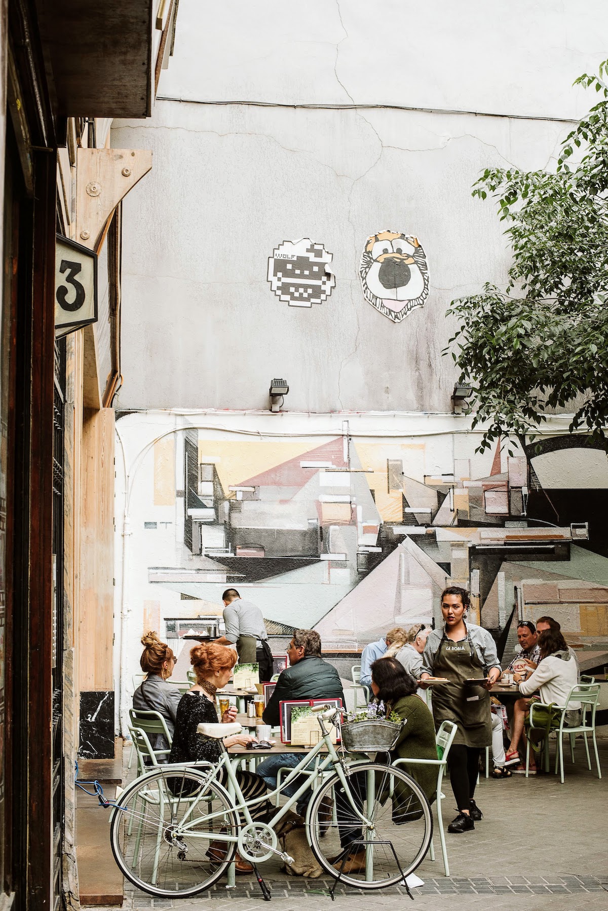 Gente comiendo y bebiendo en la terraza de un bar al aire libre.
